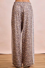 Leopard print pants on a wooden floor with a beige background