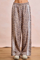 Leopard print pants on a wooden floor with a pink background
