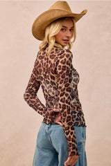 Person wearing a leopard print top and cowboy hat against a beige background