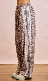 Leopard print pants with white stripes on a wooden floor and pink wall background